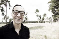 a man wearing glasses standing in a field