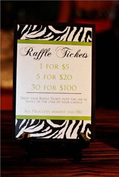 a zebra print ticket holder for raffle tickets on a wooden table with price tags