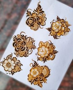 hendi tattoos are being displayed on a white sheet with gold flowers and swirls