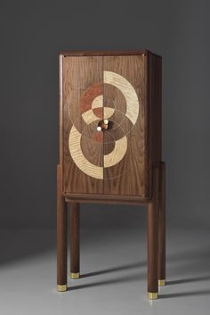 a wooden cabinet with an abstract design on the front and sides, sitting against a gray background