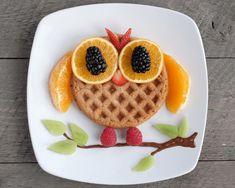 a waffle with fruit on top and eyes made to look like an owl sitting on a branch