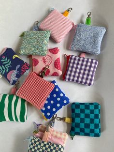 several small purses sitting on top of each other in different colors and patterns, all lined up together