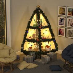 a christmas tree with presents under it in a living room next to pictures on the wall