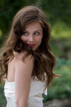 a woman in a white dress posing for the camera with her hand on her hip