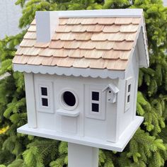 a white bird house sitting on top of a tree