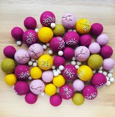 several different colored balls with white speckles on them sitting on a wooden surface