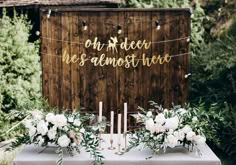 a table with flowers and candles on it in front of a wooden sign that says god is bliss