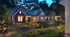 a row of houses lit up at night with lights on the windows and trees in the background