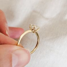 a person holding a gold ring with two diamonds on it's side and their finger