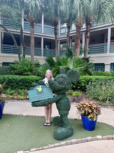 a woman standing next to a mickey mouse statue