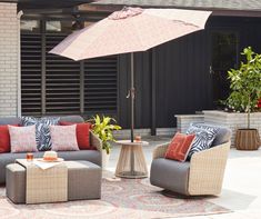 an outdoor living area with couches, chairs and an umbrella