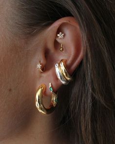 a close up of a person wearing two different types of ear piercings on their ears