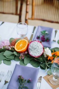 the table is set with flowers, fruit and silverware