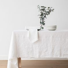 a table with a white cloth on it and a plant in the corner next to it