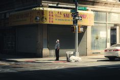 a man standing on the side of a street next to a traffic light in front of a store