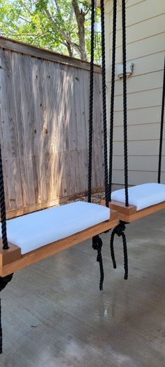 two wooden swings with white cushions on them