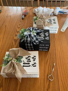 three books wrapped in burlap and tied with ribbon on a wooden table next to scissors