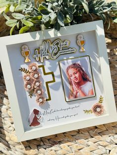 a white frame with some pictures on it and plants in the backgrouf