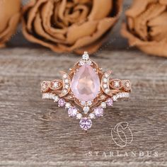 an image of a ring with pink stones on it and flowers in the back ground