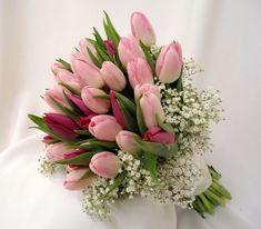 a bouquet of pink tulips and baby's breath on a white cloth