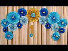 blue and gold paper flowers are arranged on the wall in front of a number one sign