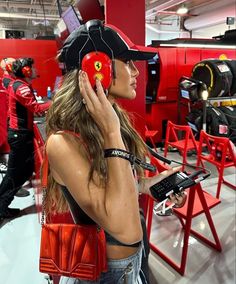 a woman wearing headphones and holding a cell phone to her ear while standing in front of red chairs