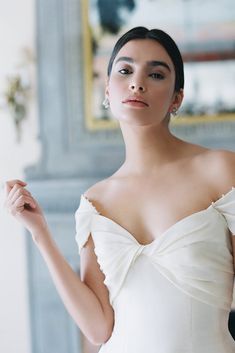 a woman in a white dress posing for the camera with her hand on her hip