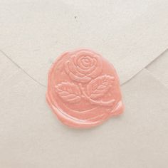 a wax stamp with a rose on it sitting in an envelope, next to a piece of paper