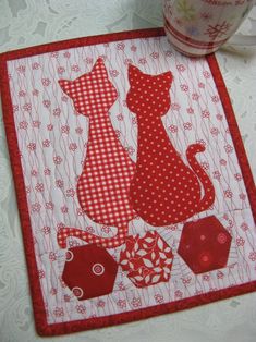 a red and white table runner with two cats on it