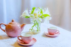 pink tea set with white flowers in vase on table