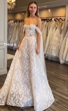 a woman standing in front of a rack of wedding dresses at a bridal shop