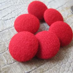 six red felt balls sitting on top of a white cloth covered tablecloth with a spoon in the middle