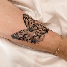 a woman's arm with a butterfly on it and a cat in the middle