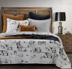 the bed is made with black and white animals on it, along with brown pillows