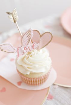 a cupcake on a plate with a heart and an arrow