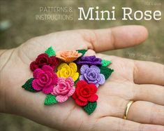 small crocheted flowers are placed on the palm of a person's hand