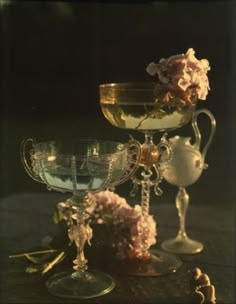 there are three wine goblets sitting on the table with pink flowers in them