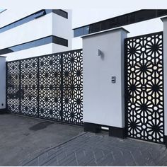 a white building with black and white laser cut screens on the front door, along with a parking lot