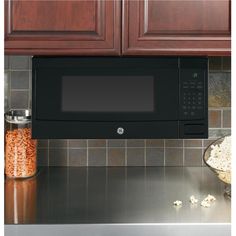 a microwave oven sitting on top of a kitchen counter next to a bowl of popcorn