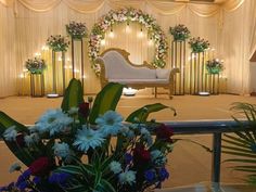 flowers and greenery are arranged in front of a stage set for a wedding ceremony