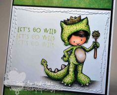 a card with a little boy dressed as a dinosaur holding a baseball bat and wearing a green costume