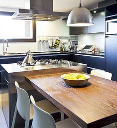 a bowl of fruit is sitting on a table in the middle of a large kitchen