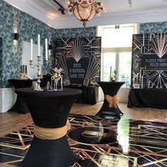 a room filled with tables and chairs covered in black cloths next to a chandelier