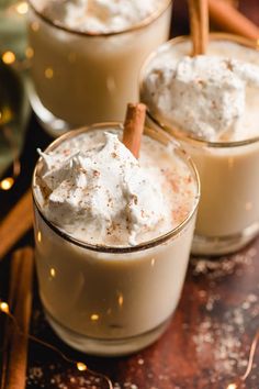 two glasses filled with whipped cream and cinnamon sticks