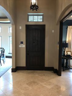 an entry way with a black door and chandelier