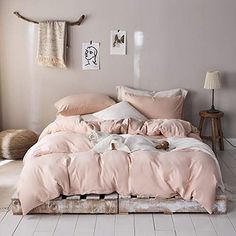 an unmade bed with pink sheets and pillows on top of it in a bedroom