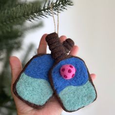 a hand holding a small felt ornament with a pink pig on it's nose