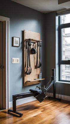 a gym room with an exercise bike and wall mounted hooks on the wall next to a window