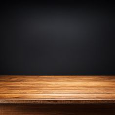 an empty wooden table against a black background