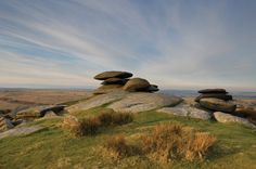 rocks stacked on top of each other in the middle of a grassy area with blue sky and clouds